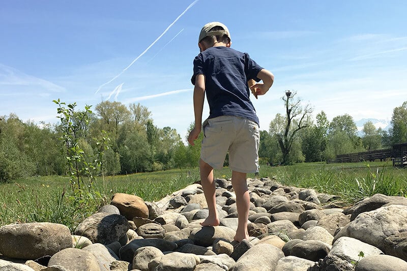 in Kind läuft barfuss über einen Naturpfad und erlebt den Ausflug voller Neugier und Freude.