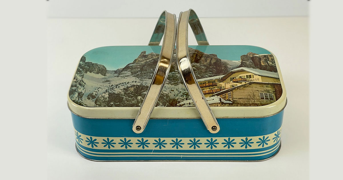 Picknick/Brotzeitdose von Mastalli Erba, bedruckt mit norditalienischem Bergpanorama und verschneiter «Pensione Riposo», circa 50er/60er Jahre. Erba in der Lombardei befindet sich unweit der Schweizer Grenze.